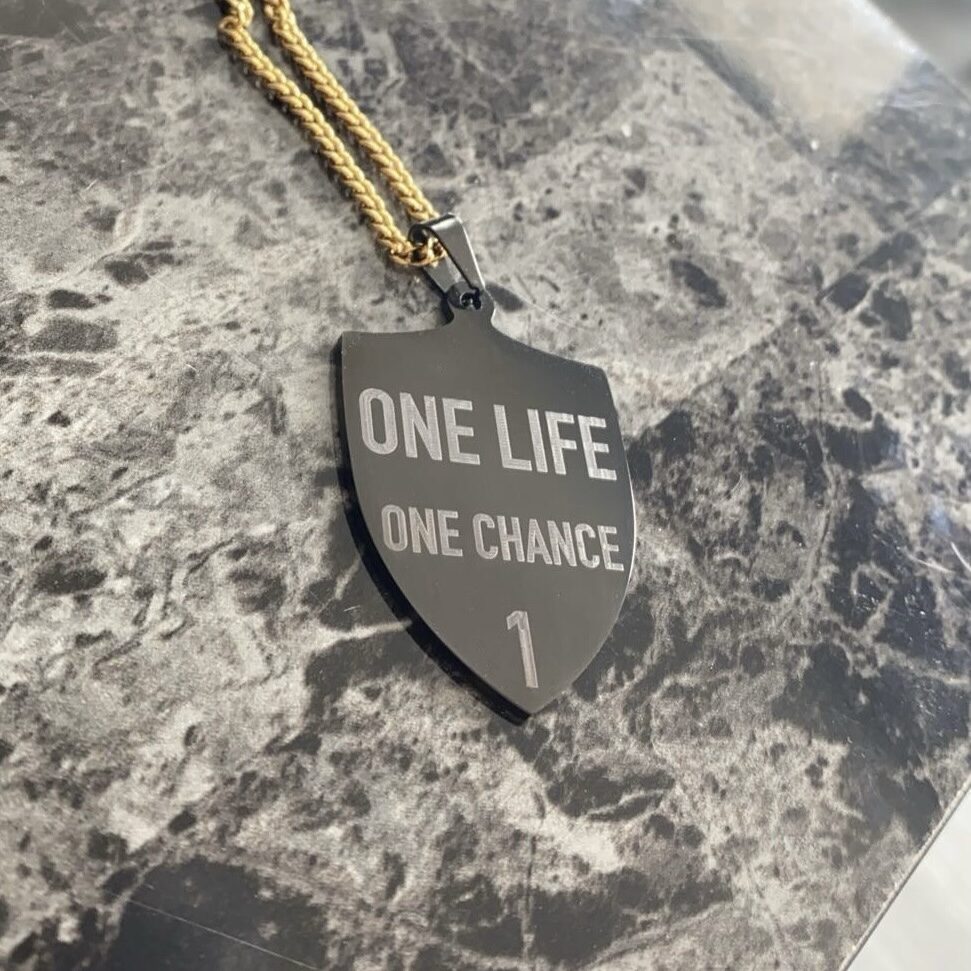 Pendentif bouclier noir gravé « One Life One Chance » sur chaîne dorée